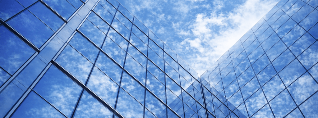 Modern glass office building facade reflecting the sky and clouds