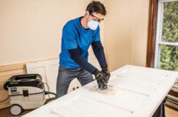 Sanding an exterior door as part of the preparation required prior to painting