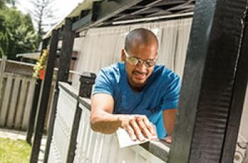 Hand sanding a deck railing with sandpaper