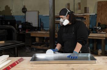 Woman finishing a metal workpiece using Norton Dry Ice PSA discs