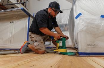 Man sanding a wood floor using an edger