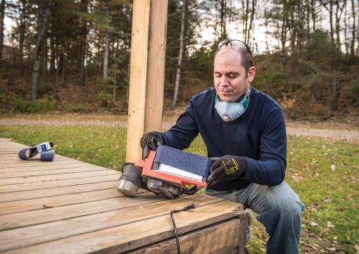 Man applying abrasive belt to a belt sander on a deck
