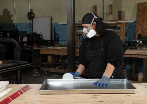 Woman finishing a metal workpiece using Norton Dry Ice PSA discs