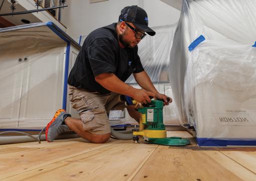 Man sanding a wood floor using an edger