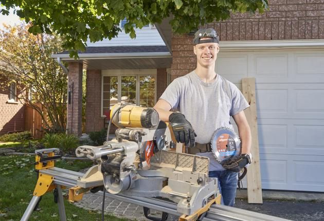 Man with wood saw blade standing in front of a table saw