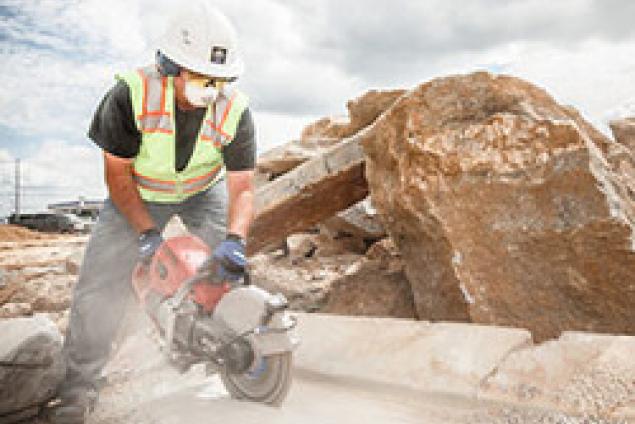 Construction worker using a gas saw to cut concrete
