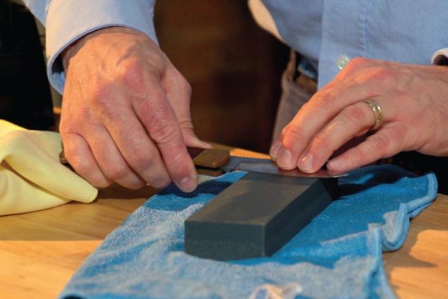 Man sharpening knife on benchstone in sweeping motion
