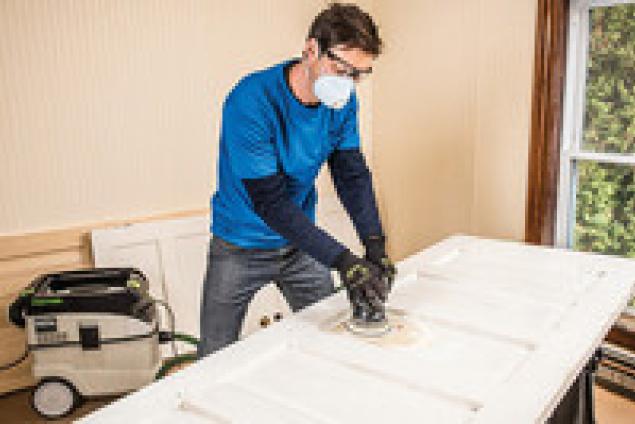 Sanding an exterior door as part of the preparation required prior to painting