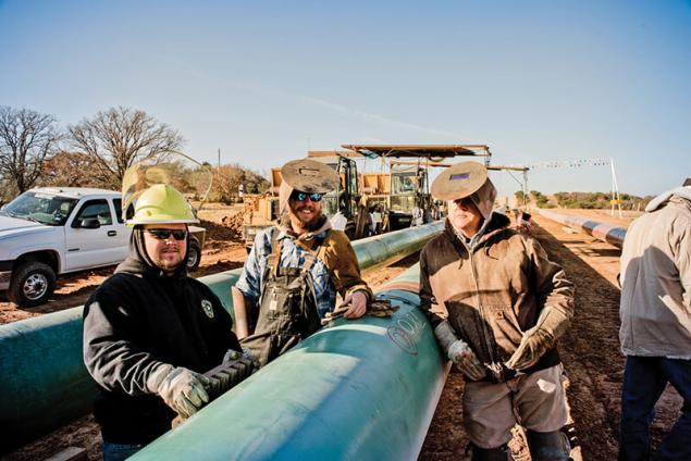Image of 3 welders posing by a pipeline