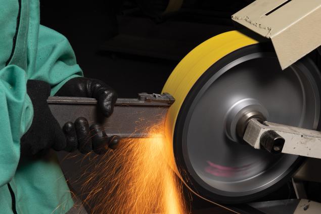 Operator using a Norton RazorStar belt on a backstand grinder