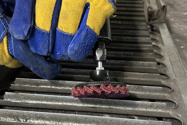 Operator using a maroon Norton Vortex Rapid Prep mini flap disc