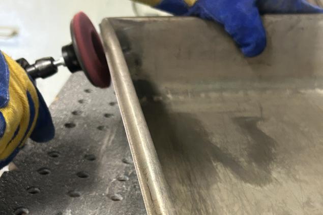 Operator using a Norton Vortex Rapid Prep mini flap disc to grind and finish a radiused part