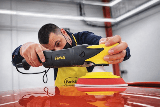 Using a Farécla polisher to refine and finish the surface of a car panel in an automotive workshop.