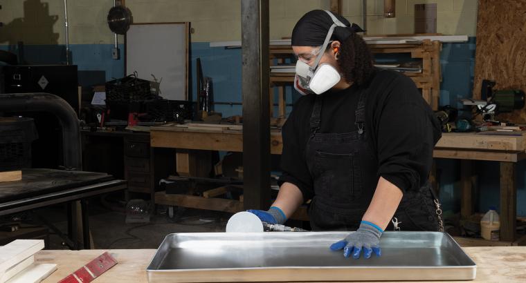 Woman finishing a metal workpiece using Norton Dry Ice PSA discs