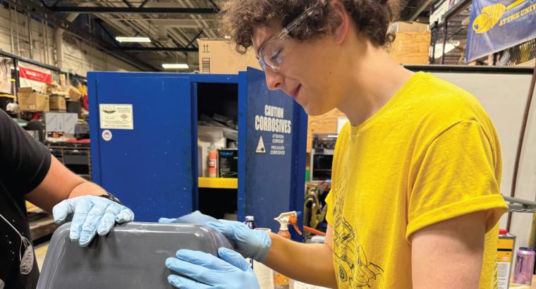 University team member sanding car part