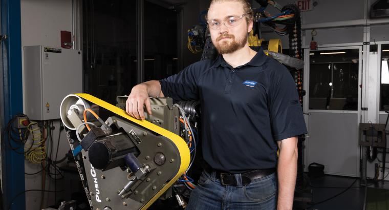 engineer leaning on robotic arm in lab